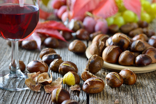 Geröstete Maroni mit neuem Rotwein, weiße und rote Weintrauben im Hintergrund photo