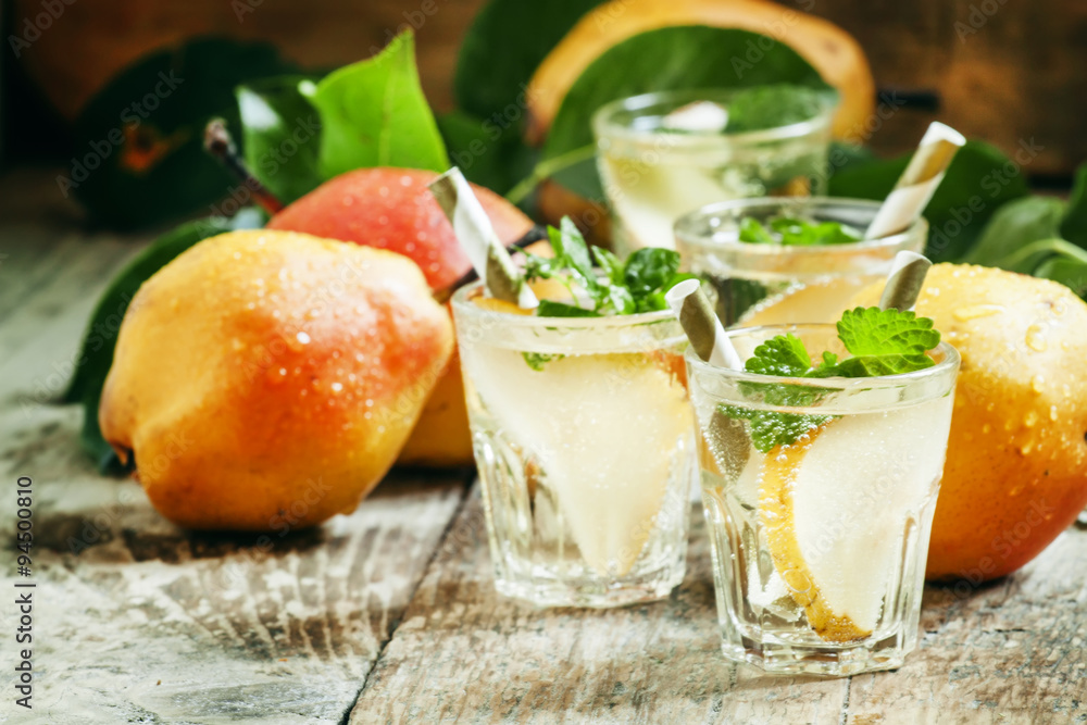 Pear cocktail with soda, fruit slices and mint on an old wooden Pear cocktail with soda, fruit slices and mint on an old wooden