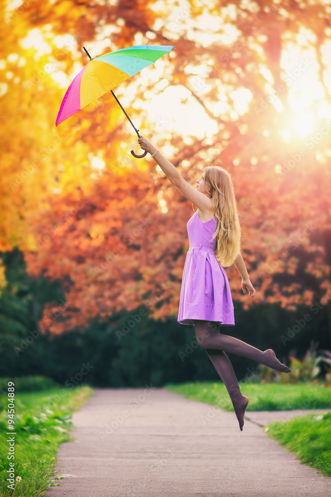 Outdoor photo from a girl fly away with a colorful umbrella in a beautiful  park at autumn, sunset in the background. Stock-foto | Adobe Stock