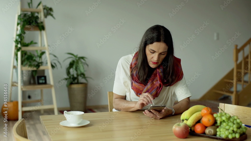 Woman sitting at the table and texting on smartphone
Woman sitting at the table and texting on smartphone