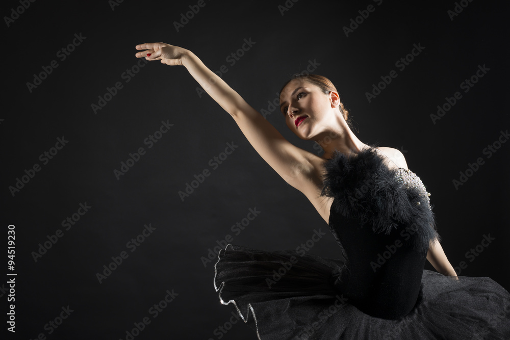 Fototapeta premium Beautiful ballerina in the role of a black swan, wearing black tutu on black background