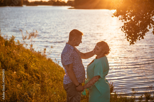 Romantic couple standing and kissing on background summer lake sunset