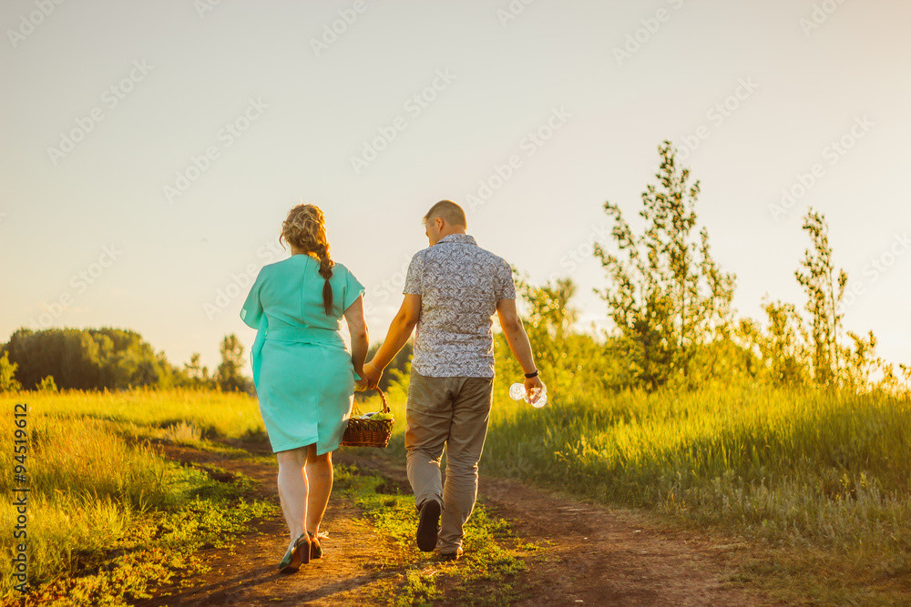 Romantic couple go and holding hands on background summer meadow Romantic couple go and holding hands on background summer meadow