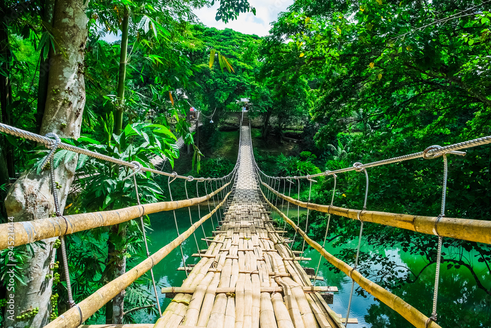 Fototapeta premium Bamboo pedestrian suspension bridge over river