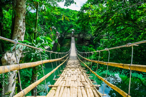 Fototapeta Naklejka Na Ścianę i Meble -  Bamboo pedestrian suspension bridge over river