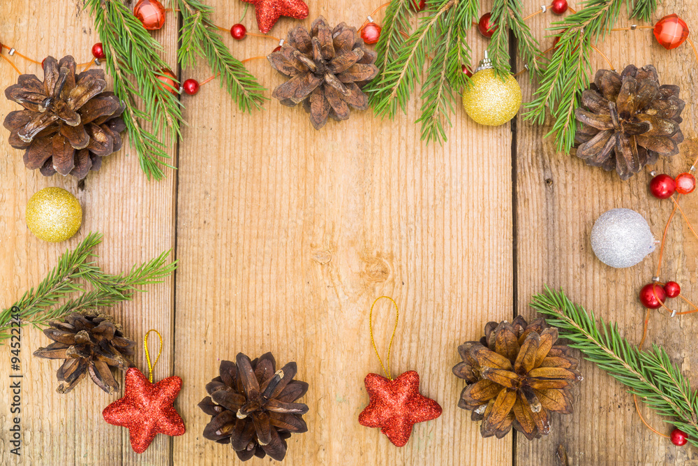 Fototapeta premium Christmas decoration on rustic wooden desk (pine cones, cinnamon, anise, spruce branches, red stars).