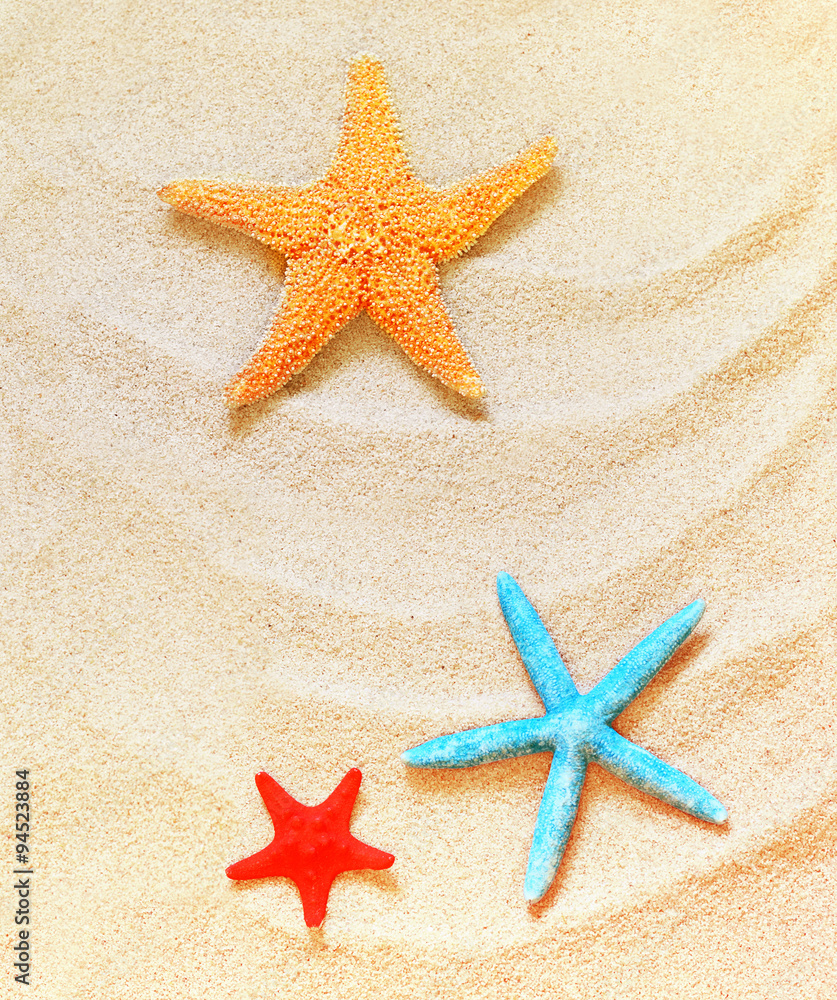 Red, blue and yellow starfish on the sandy beach Red, blue and yellow starfish on the sandy beach