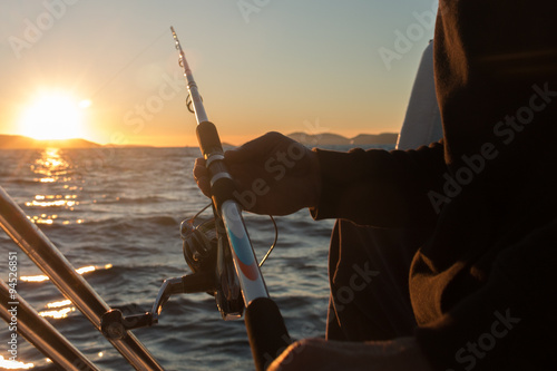 Man's hand with a fishing equipment in sunset