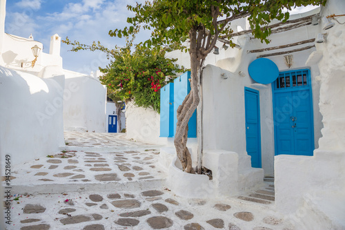 Mykonos tradycyjny biały streetview z niebieskimi drzwiami i drzewami, Grecja