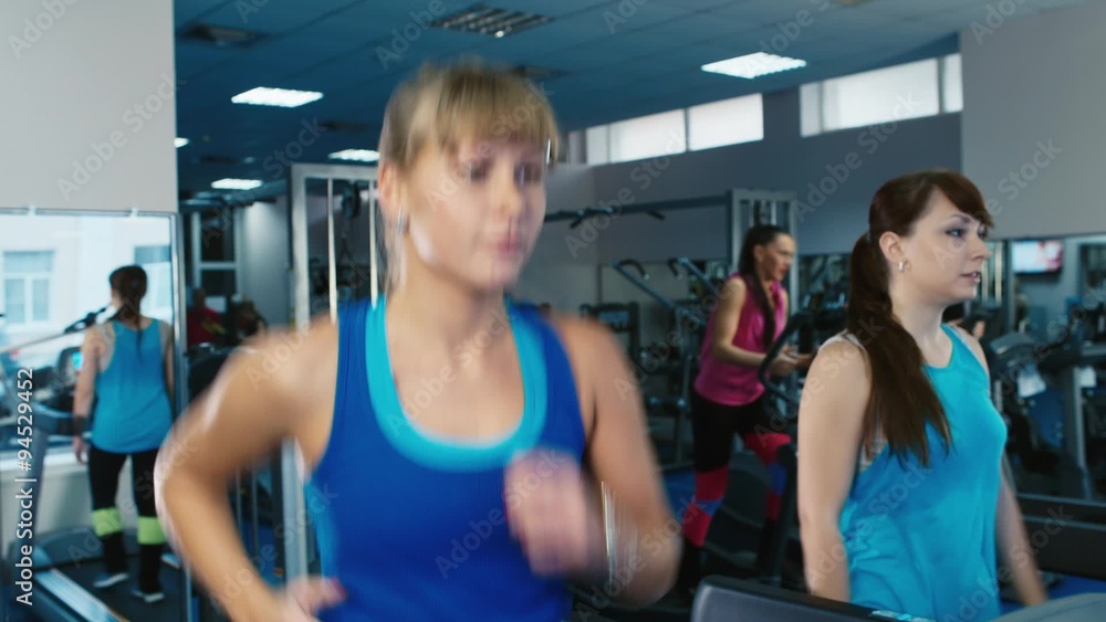 Two attractive girls exercise on a treadmill at the gym Two attractive girls exercise on a treadmill at the gym