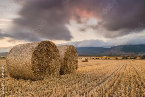 Straw bales in the field at sunset with dramatic sky