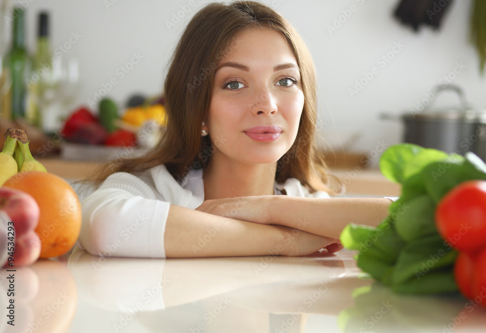 Young woman standing near desk in the kitchen . Young woman standing near desk in the kitchen .