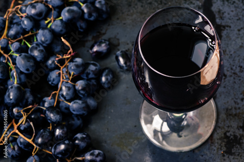 Wineglass of red wine with grapes photo