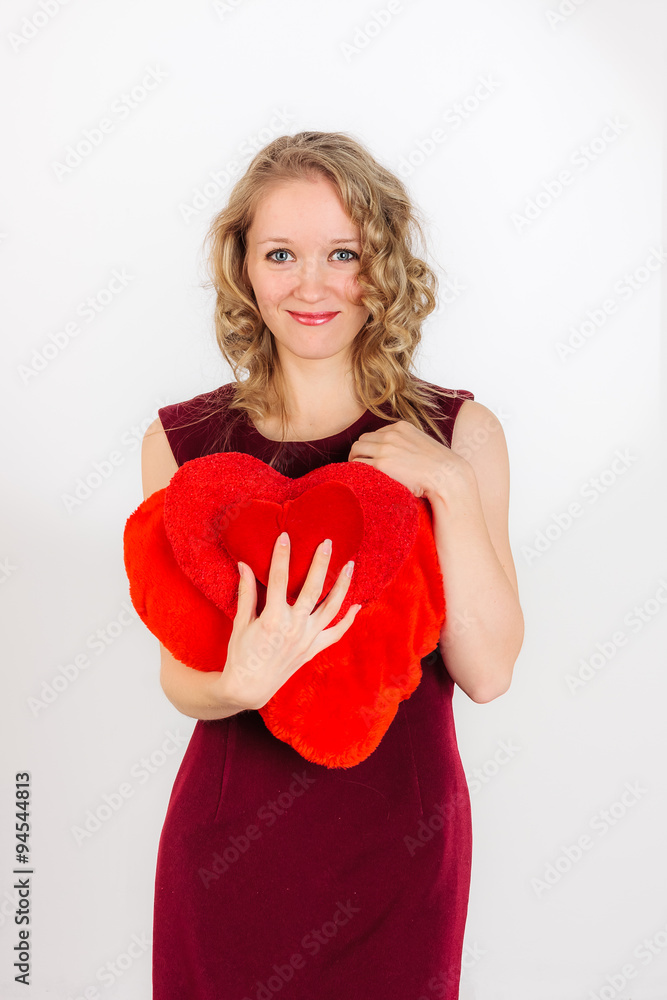 Beautiful blonde woman standing with red decorateve pillows Beautiful blonde woman standing with red decorateve pillows