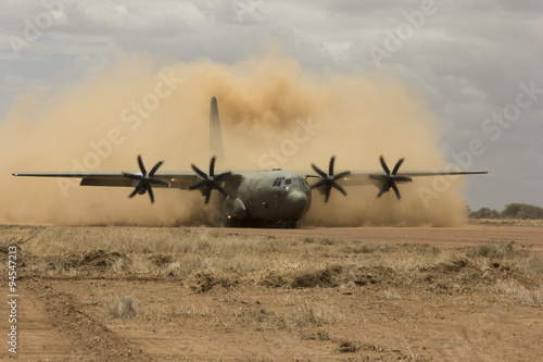 Air force plane lands on desert field airstrip to deploy troops photo