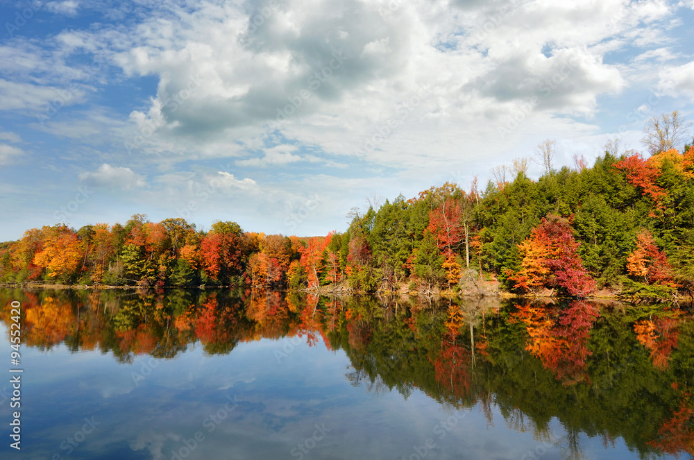 Fototapeta premium Beautiful autumn lake reflecting red fall colors in its clear water