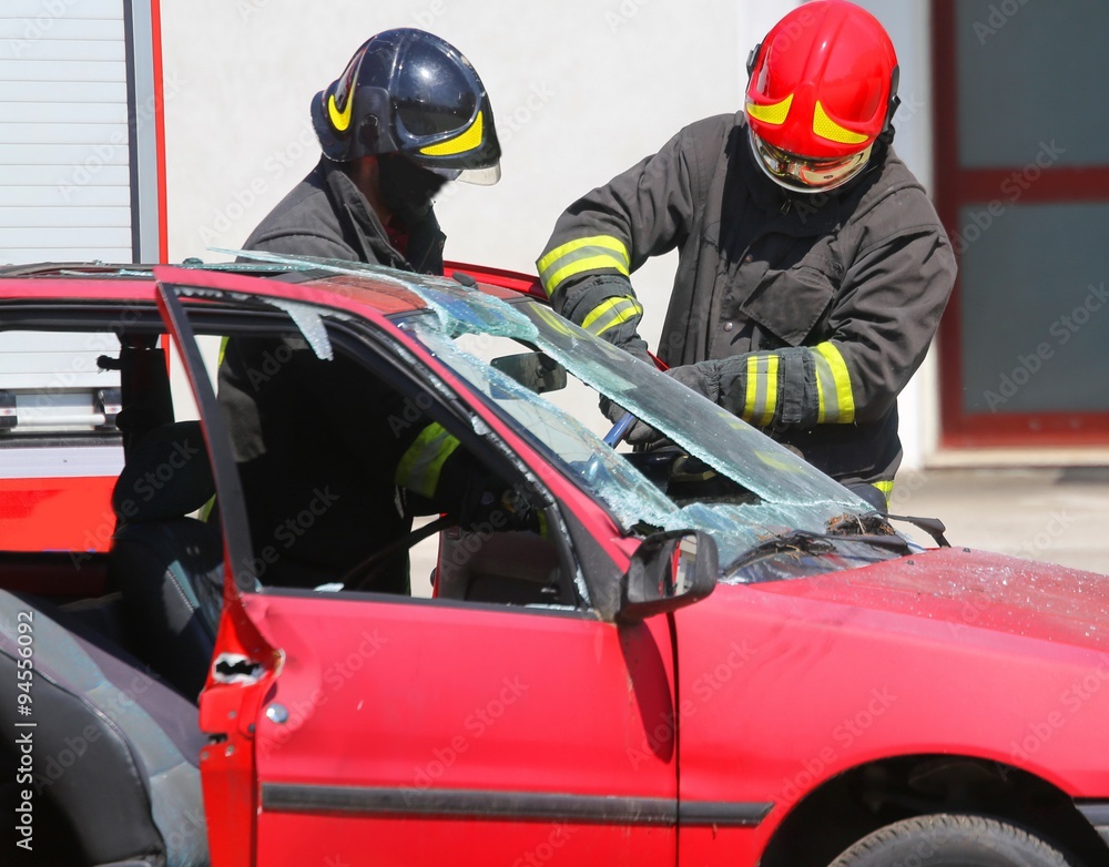 chief fireman whit red helmet while breaking the windshield of a