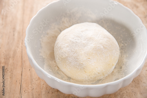 Gnocchi dough in white ceramic bowl on wood