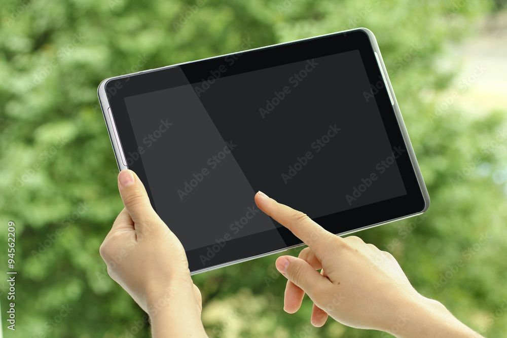 woman wants to touch your finger to the screen of the tablet on a background of leaves woman wants to touch your finger to the screen of the tablet on a background of leaves