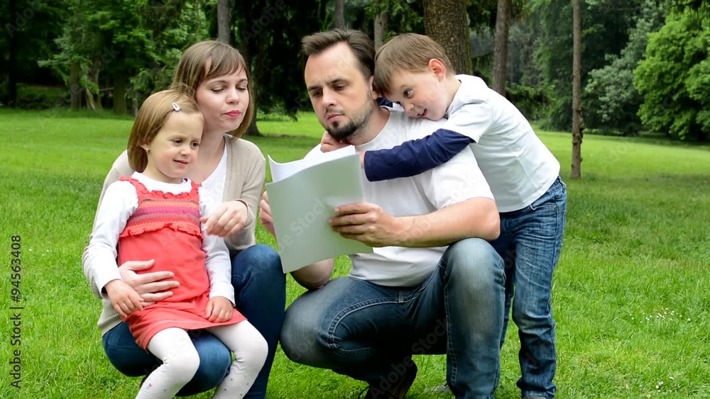 family (middle couple in love, cute girl and small boy) read document in the park family (middle couple in love, cute girl and small boy) read document in the park
