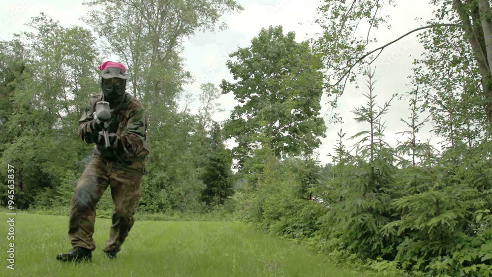 A man in camouflage is in action playing paintball. It is a friendly game with no harm at all A man in camouflage is in action playing paintball. It is a friendly game with no harm at all