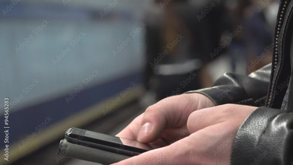 man works (typing) on smartphone - subway station - incoming metro - closeup man works (typing) on smartphone - subway station - incoming metro - closeup