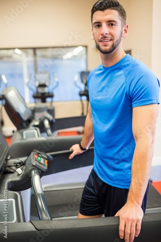 Smiling man standing on a treadmill