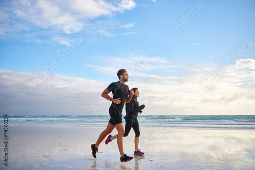 Man and woman confidently running on the beach