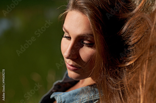 молодая девушка с длинными волосами у озера в солнечную погоду