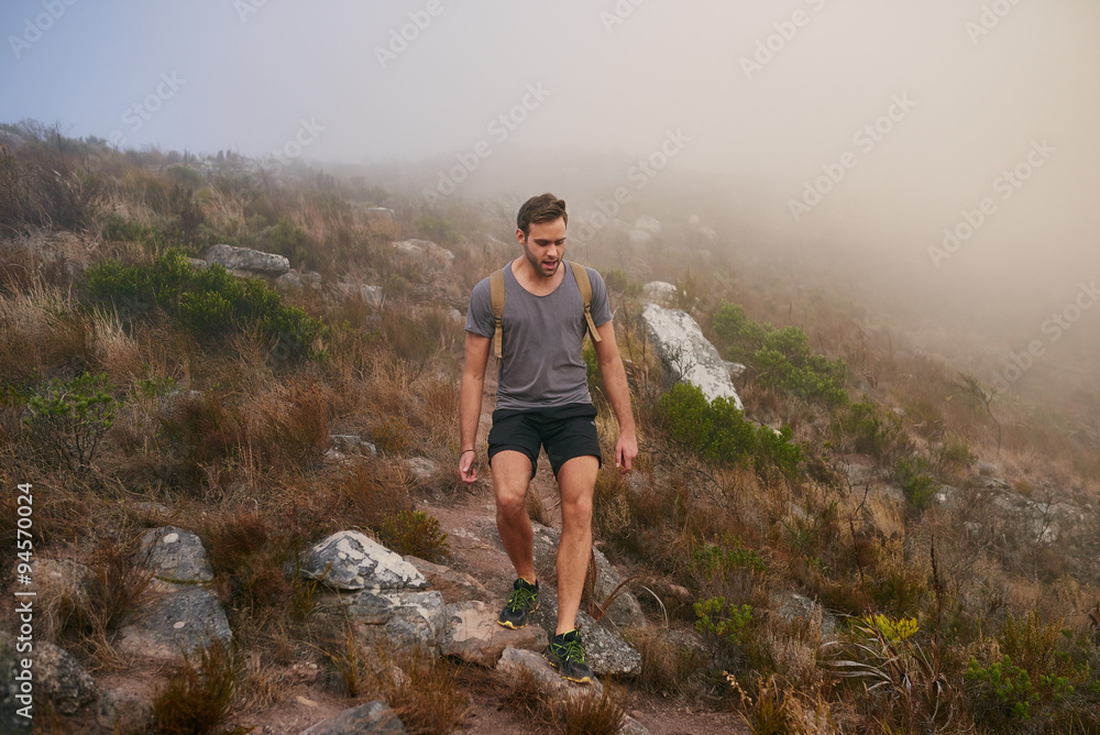 Young man carefully making his way over a stony mountain trail Young man carefully making his way over a stony mountain trail