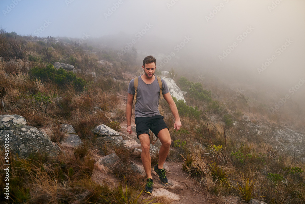 Young man walking on a stony mountain path in mist