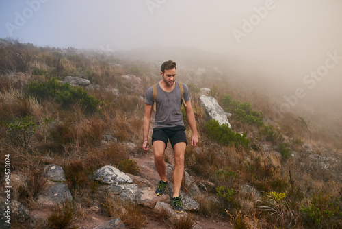 Young man carefully making his way over a stony mountain trail