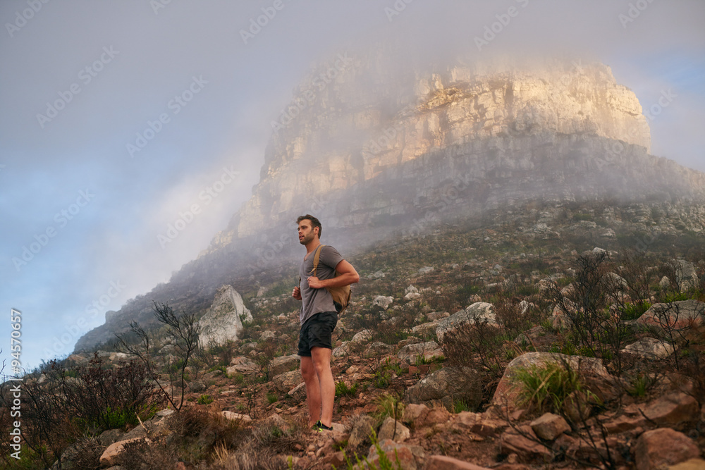 Obraz premium Young hiker on a nature trail with a mountain behind him