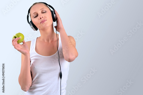 Attractive athletic blondy woman holding a bitten apple and list photo