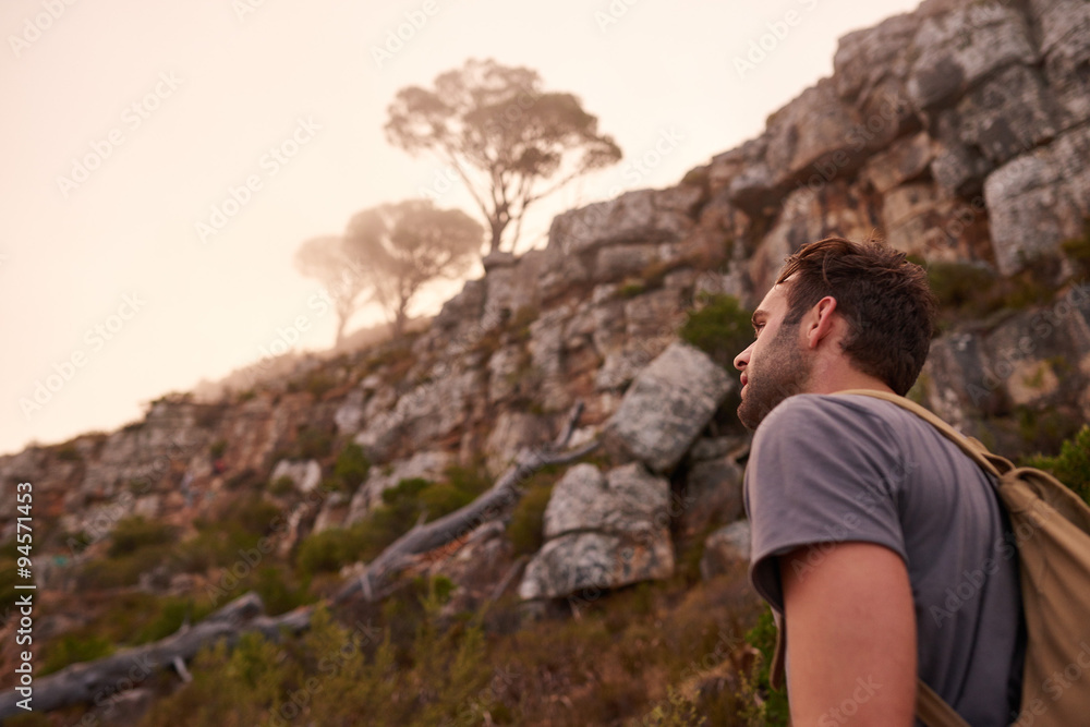 Young man walking with a misty mountain in view Young man walking with a misty mountain in view