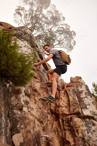 Young man climbing rocks on a mountain nature trail