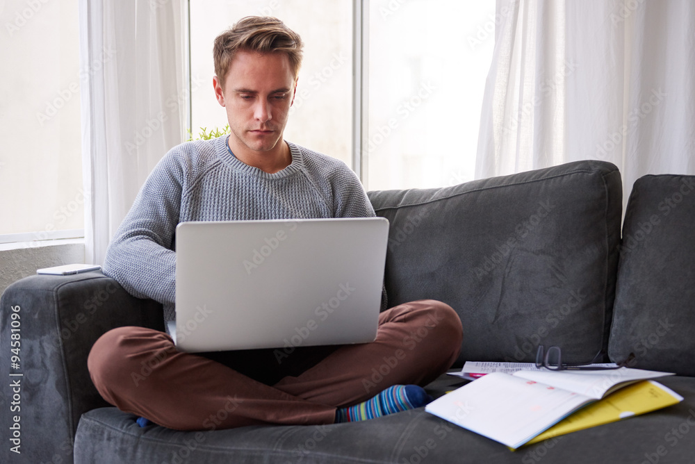 Student studying with his laptop on his couch Student studying with his laptop on his couch