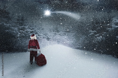 Composite image of santa carrying sack of gifts  photo