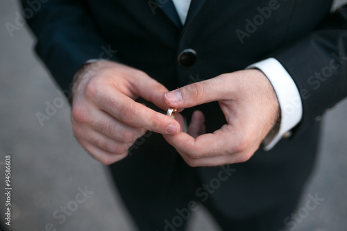 groom holding a wedding ring © teksomolika