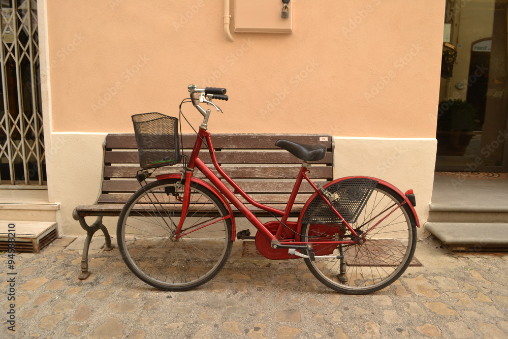 Rotes Fahrrad vor alter Holzbank