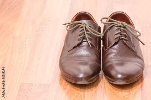 A pair of men's brown leather shoes on wooden floor