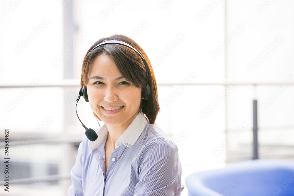 Asian Business woman talking using her headset in the office Asian Business woman talking using her headset in the office