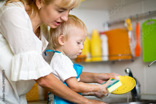 Φωτογραφία Mother teaches her little child son to wash-up