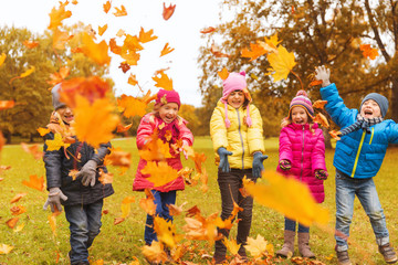 happy children playing with autumn leaves in park
