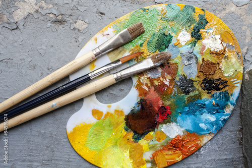 Brushes and colorful abstract oil colors paiters pallet, on grunge background