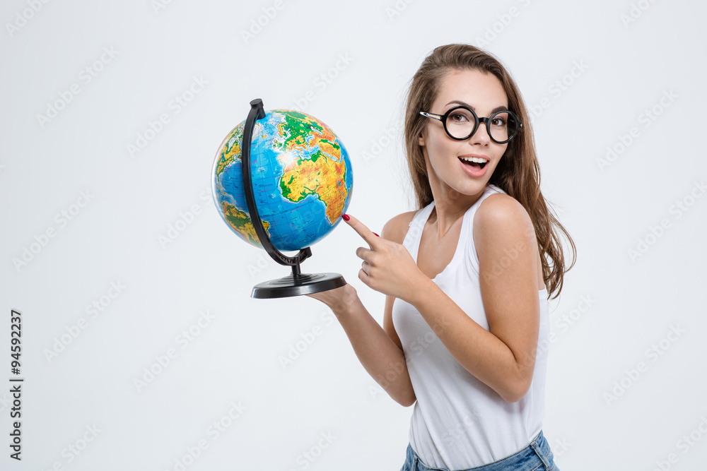Fototapeta premium Woman pointing finger on globe and looking at camera