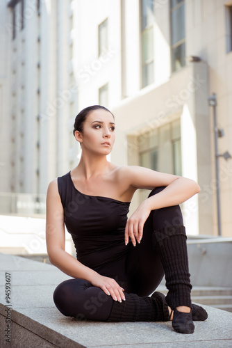 Graceful attractive ballerina sitting on the balusters