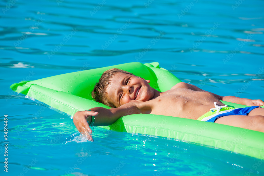 Small boy relaxing on green inflatable mattress