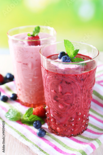 Glasses of berry smoothie on wooden table on blurred background