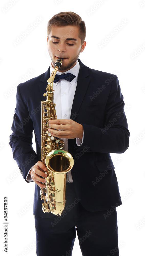 Fototapeta premium Young male musician playing golden brass saxophone in formal suit and bow tie, isolated on white background
